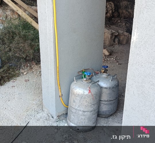 שני בלוני גז ליד קיר עם צינור צהוב
